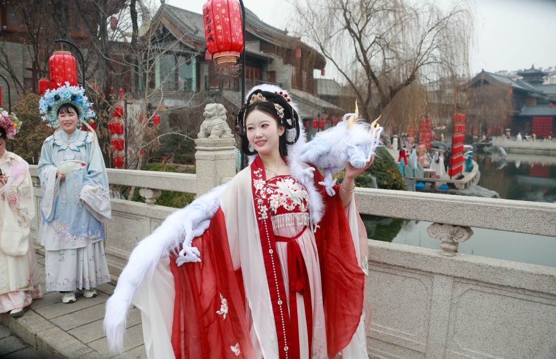 在洛邑古城景区，一位游客身穿汉服、身披龙形配饰打卡拍照。人民网记者 慎志远摄
